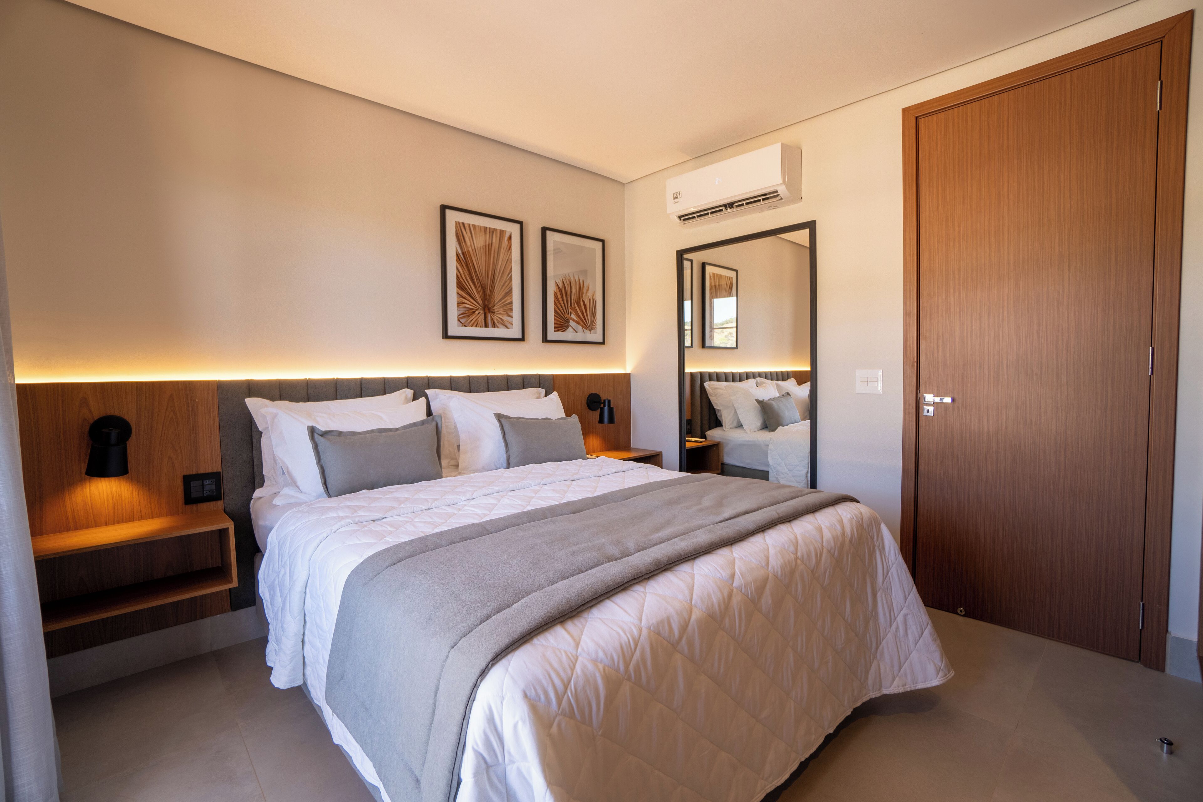 Un dormitorio moderno con una cama grande, mesitas de noche, un armario y una obra de arte en la pared.