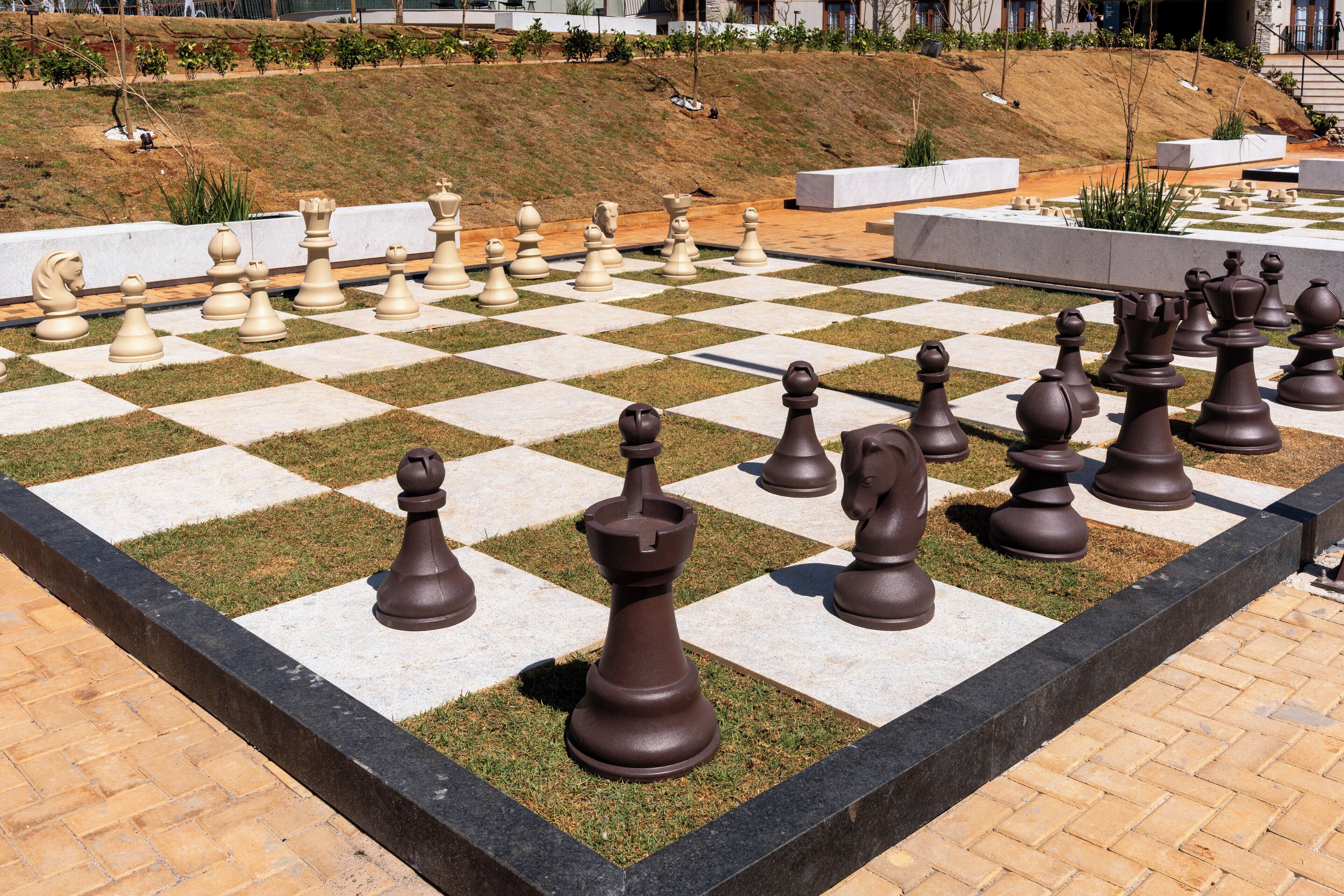 A large outdoor chessboard with chess pieces arranged for a game.