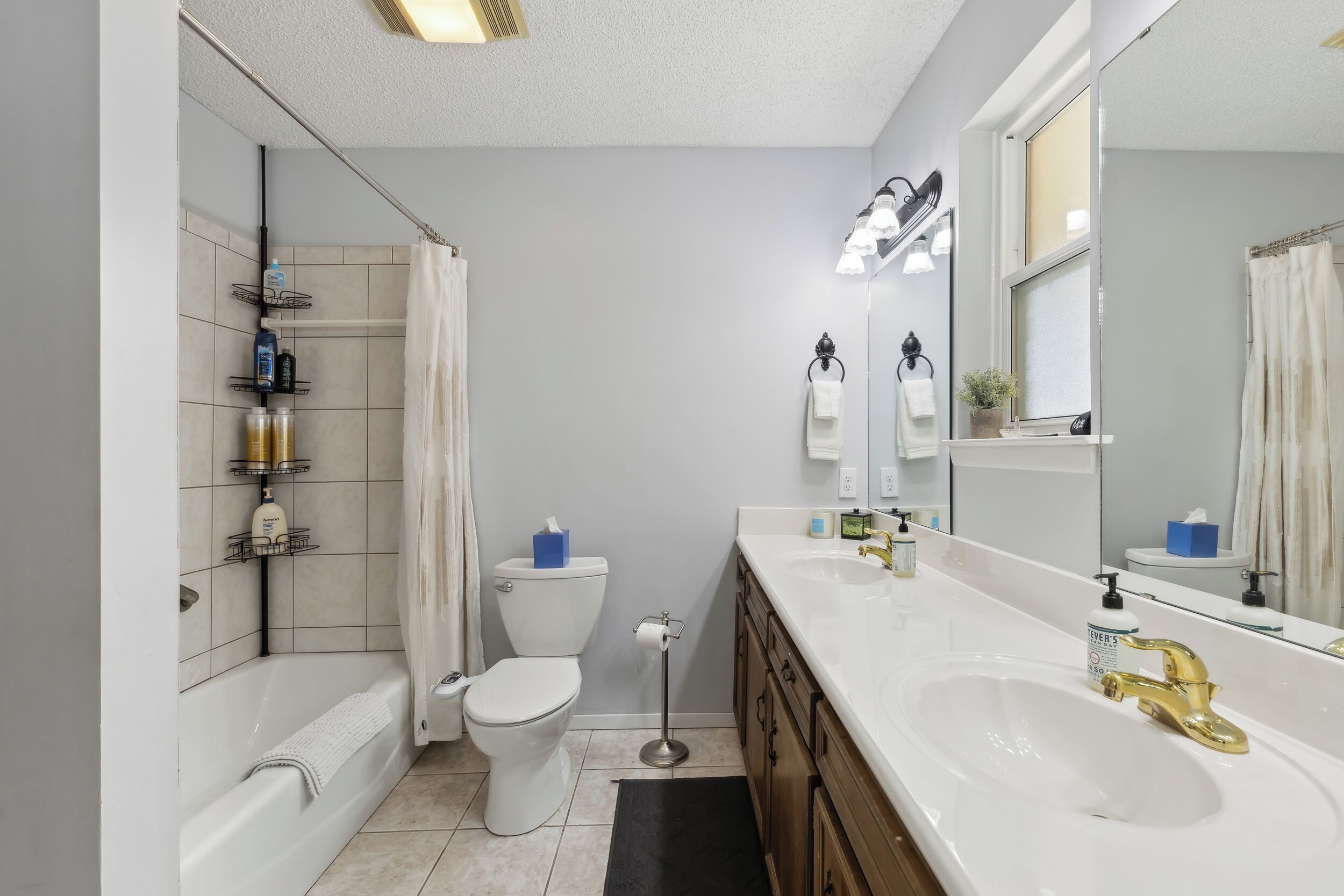 A modern bathroom with a bathtub, toilet, and a large sink with a gold faucet.