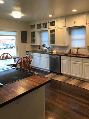 A modern kitchen with white cabinetry, a wooden countertop, and a built-in dishwasher. - Cute 2 Bedroom House Close to BYU, downtown Provo, UVU, Freeway (Provo)