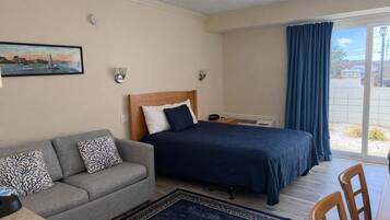 Un dormitorio con cama, sofá, escritorio y vistas al exterior.