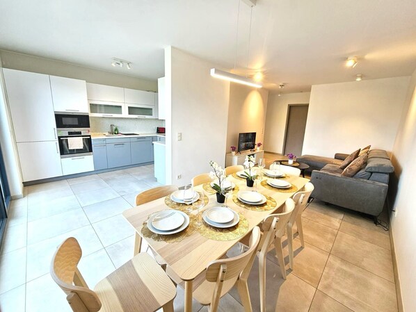 A modern apartment with a dining area, kitchen, and living space. - Stylish 3 BR with 2 terraces and parking (Luxembourg City)