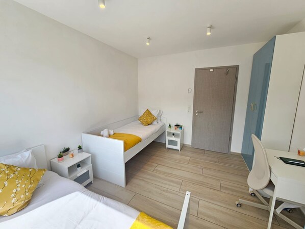 A modern bedroom with a bed, bedside table, and a desk with a chair.