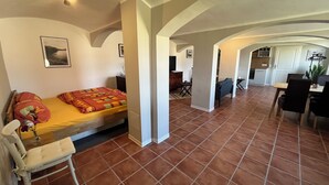 Un grand espace de vie comprenant un lit, une table à manger et une cuisine à l’arrière-plan.