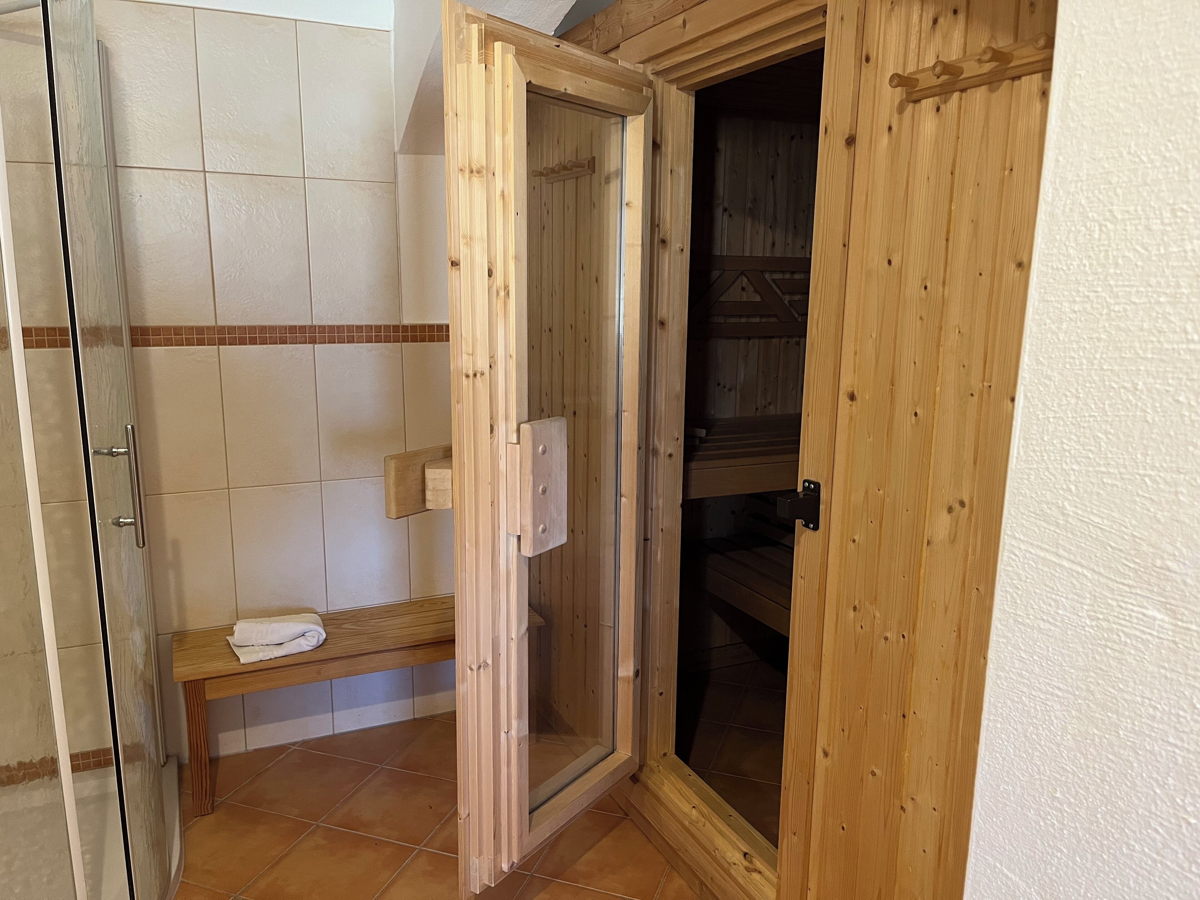 Ein Holzsaunaraum mit Bank, Handtuch und Holztür.