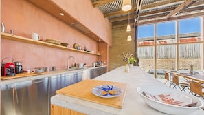 A modern kitchen with a large island, stainless steel appliances, and a view of the outside through large windows. - South Barns a Spacious Barn Conversion Near Cowes (Cowes)