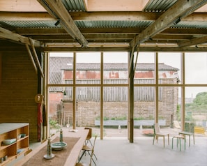 A spacious room with a large window, a wooden table, and chairs. - South Barns a Spacious Barn Conversion Near Cowes (Cowes)