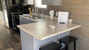 Una cocina con encimera de granito, pileta de acero inoxidable y taburetes de madera.