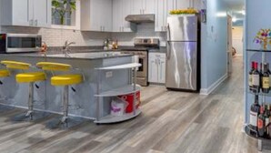 Een moderne keuken met witte kastjes, roestvrijstalen apparatuur en een centraal kookeiland met barstoelen.
