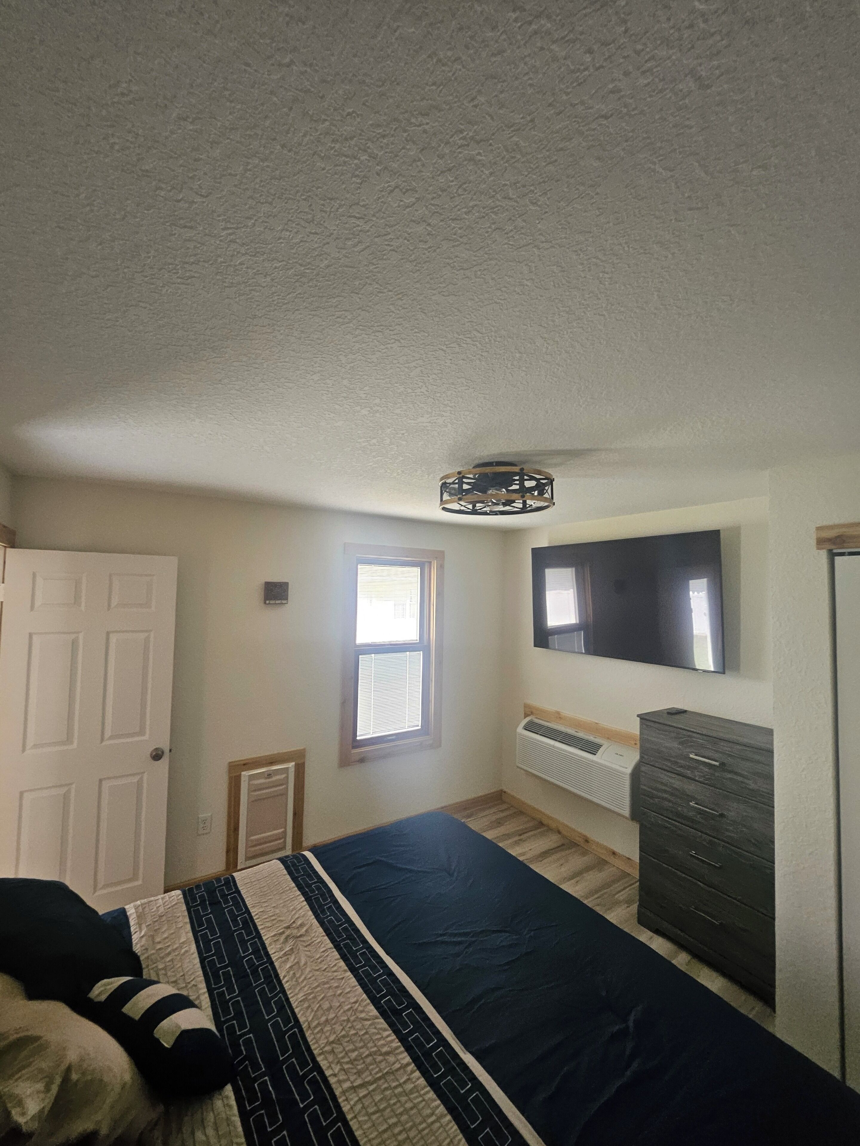 Ein Schlafzimmer mit Bett, Kleiderschrank, Fenster und Deckenventilator.