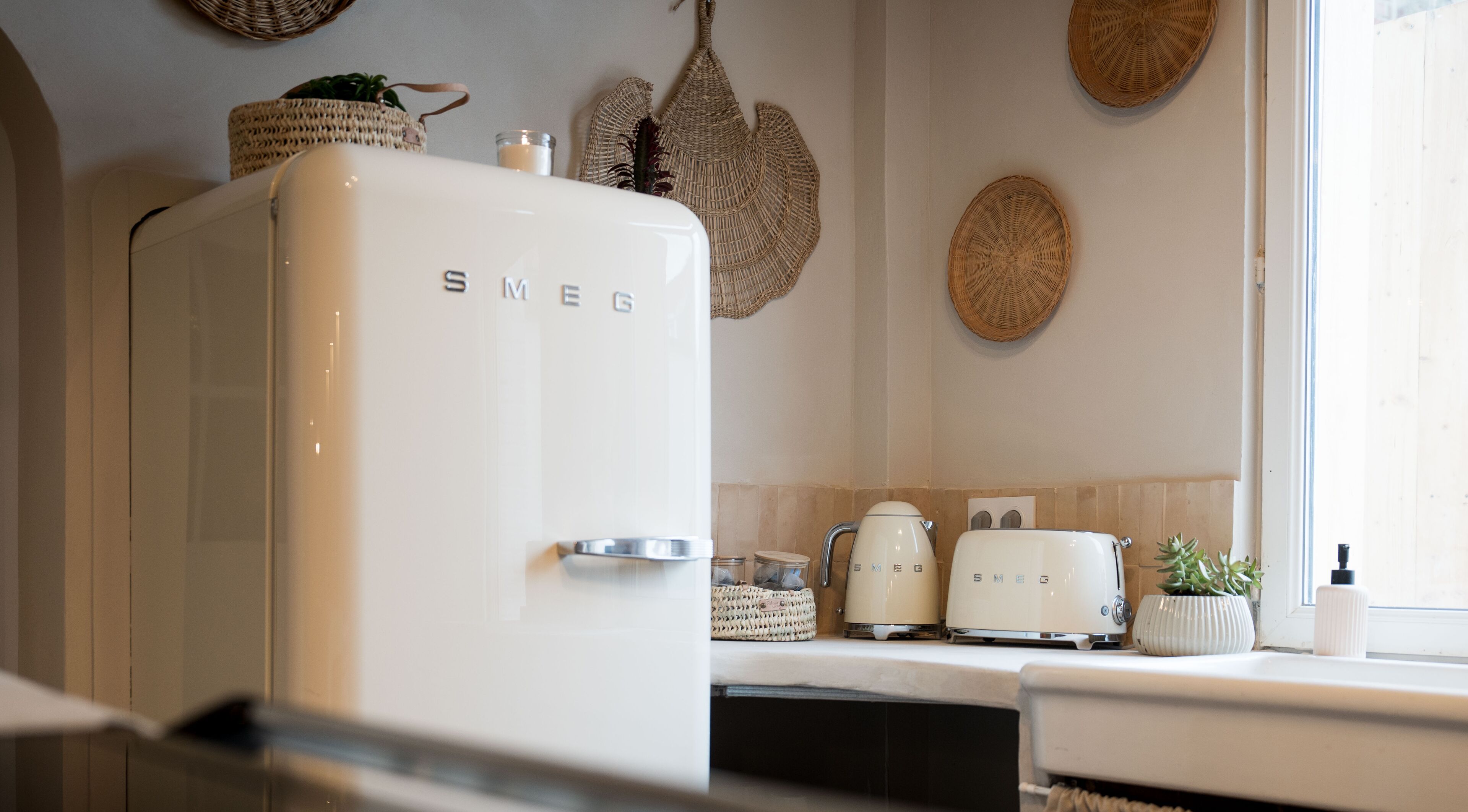 A kitchen with a white Smeg refrigerator, a toaster, and a kettle on the counter.