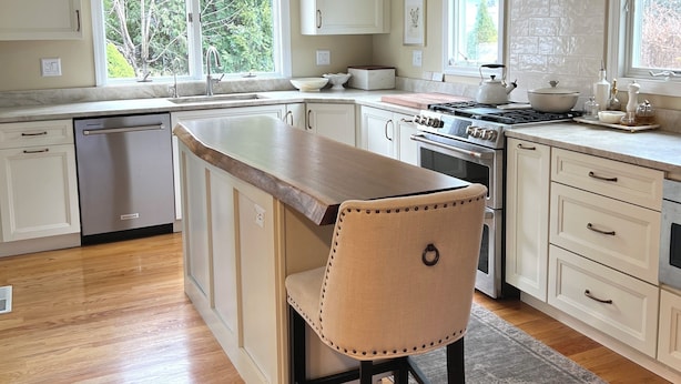 A modern kitchen with a central island, stainless steel appliances, and large windows.