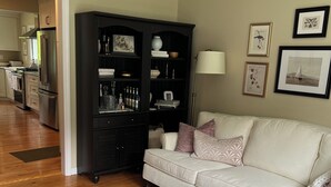 A living room with a beige sofa, a marble coffee table, a dark wooden cabinet, and a floor lamp.