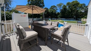 Een overdekt terras buiten met rieten meubilair, een tafel en een parasol.