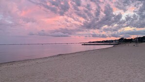 Een strand met een rustige zee, een steiger en een bewakingspost.
