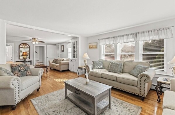 A spacious living room with a beige sofa, a wooden coffee table, and a chandelier.