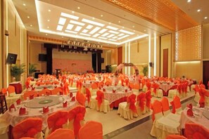 A banquet hall with round tables and chairs, a stage, and a large screen. - Shanhai Holiday Hotel (Qinhuangdao)