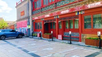 A red building with traditional Chinese architectural elements, a parking lot, and a blue car.
