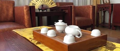 A traditional tea set on a tray, a fan, and a table with a yellow tablecloth in a room with wooden furniture.