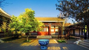 Un patio tradicional con una fuente central, rodeado de edificios con tejados de azulejos y construcciones de madera.