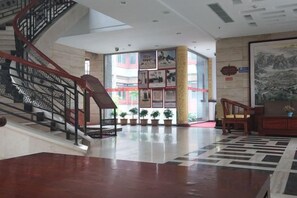 A spacious lobby with a staircase, a large wall with framed pictures, and a seating area. - Shanhai Holiday Hotel (Qinhuangdao)