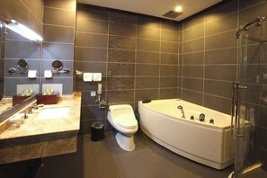 Une salle de bain moderne avec une grande baignoire, des toilettes et une douche à parois de verre.