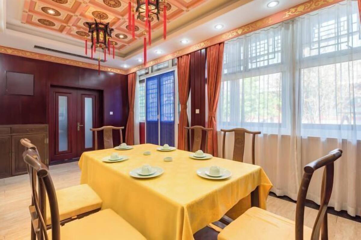 Comedor con una mesa dispuesta para seis personas, sillas de madera y un diseño de techo tradicional.