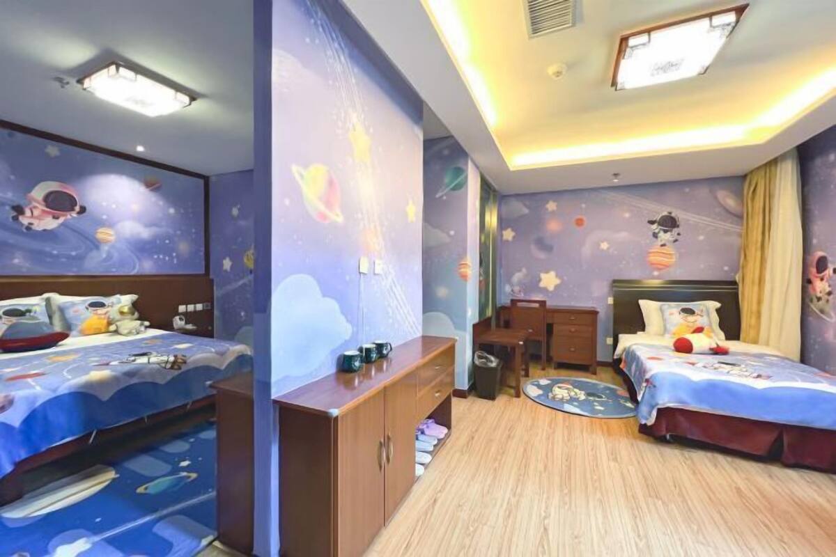 Una habitación infantil con literas, un escritorio y un mural con motivos espaciales.
