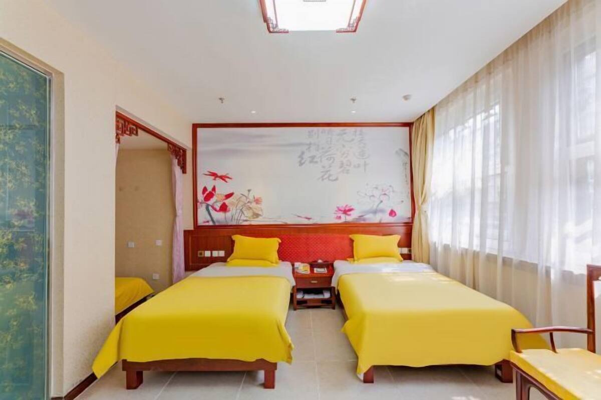Una habitación de hotel con dos camas, un cuadro grande en la pared y una ventana con cortinas.