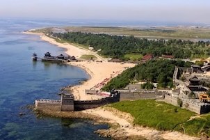 Zona costera con una estructura fortificada, una playa y una zona boscosa.