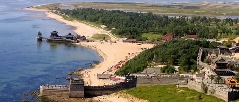 Une zone côtière comprenant une plage, une structure fortifiée et une végétation luxuriante environnante.