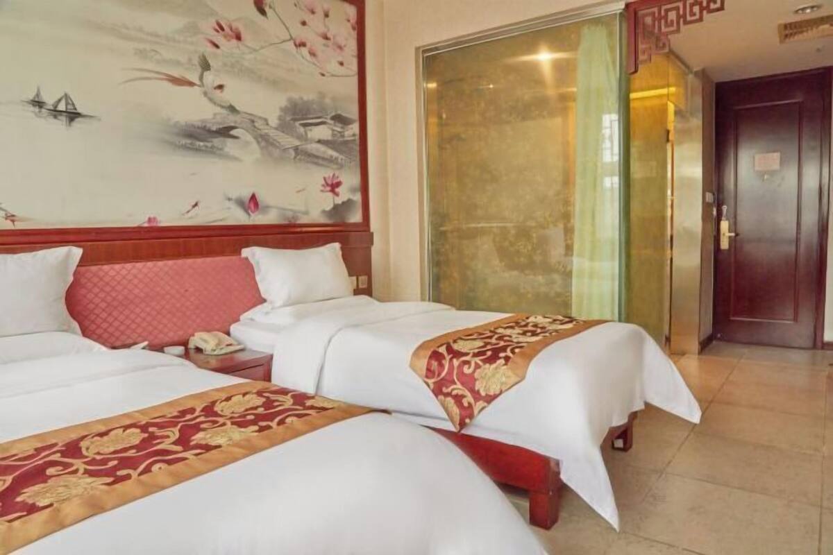 Una habitación de hotel con dos camas, una mesita de noche, un teléfono y un cuadro decorativo en la pared.