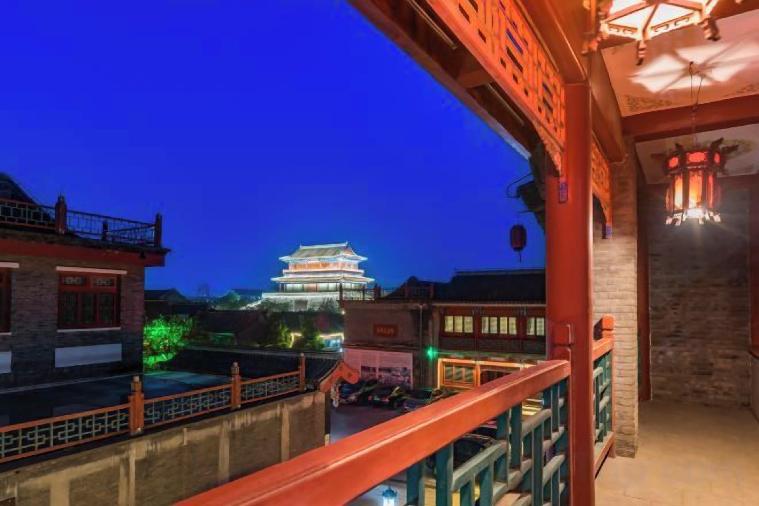 A traditional building with illuminated windows and a balcony overlooking a street at night.