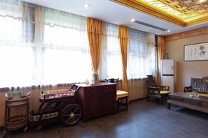 A room with a traditional design, featuring a sofa, a small table, a cabinet, and a decorative cart. - Shanhai Holiday Hotel (Qinhuangdao)