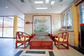 Un vestíbulo con una mesa de centro de madera, dos sillas de madera, un cuadro grande enmarco y un ventanal con vistas.