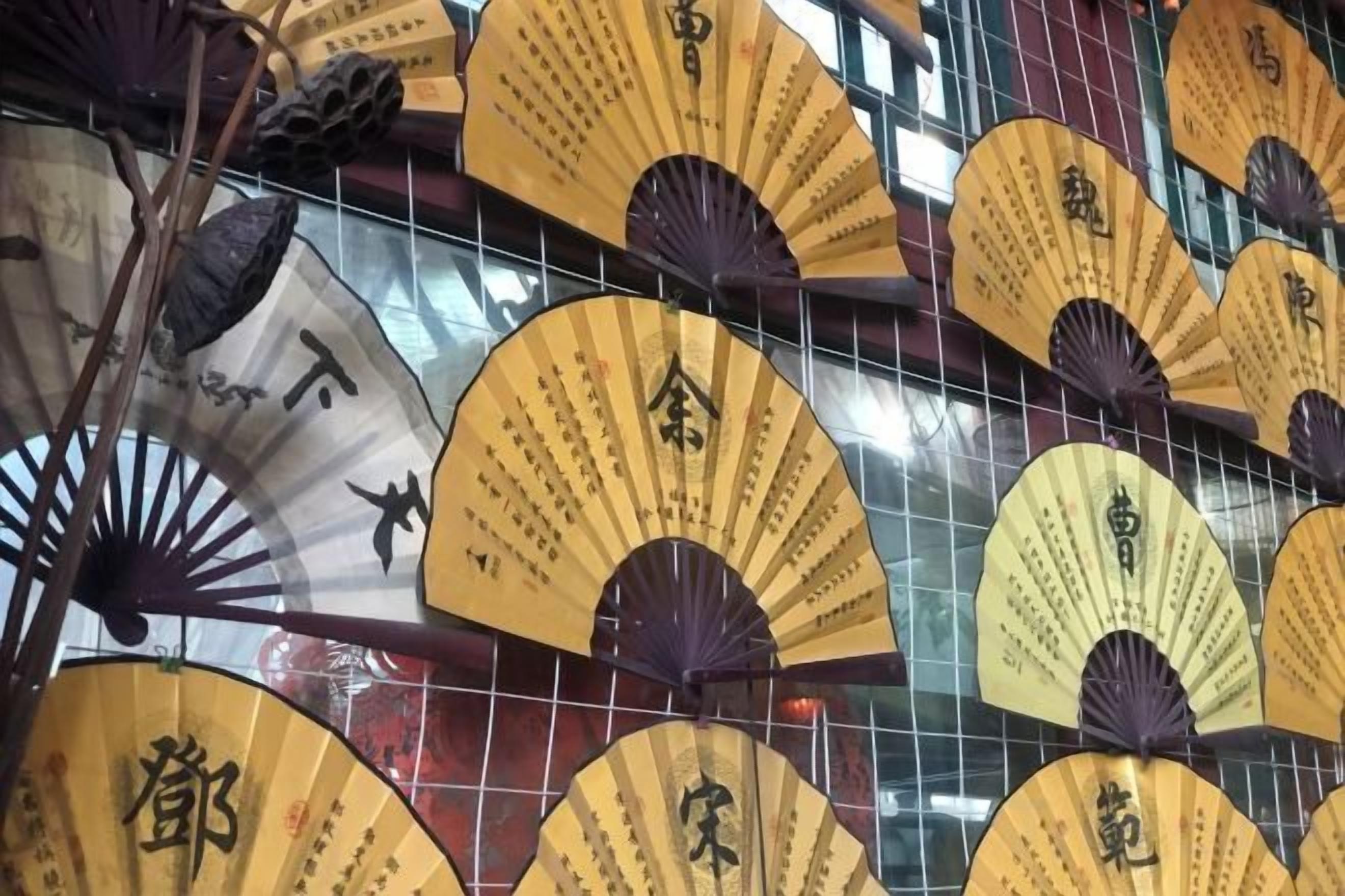 A wall with multiple traditional fans, each with Chinese calligraphy.