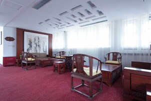 Una habitación tradicional con alfombra roja, muebles de madera y un cuadro grande en la pared.