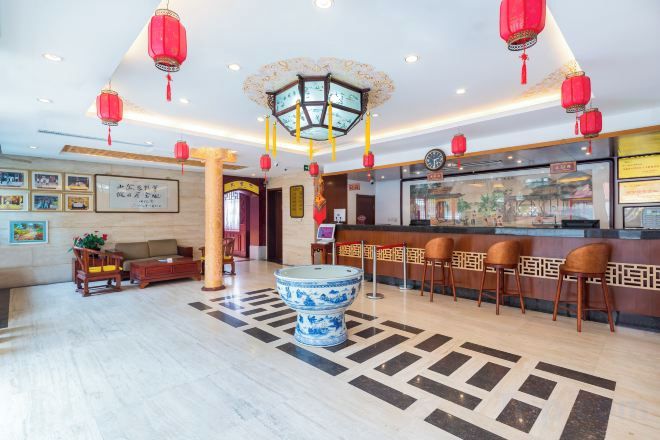 A hotel lobby with a reception desk, seating area, and a decorative blue and white urn.