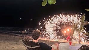 Un espace de restauration situé au bord de la plage, avec des tables en plein air et des guirlandes lumineuses.