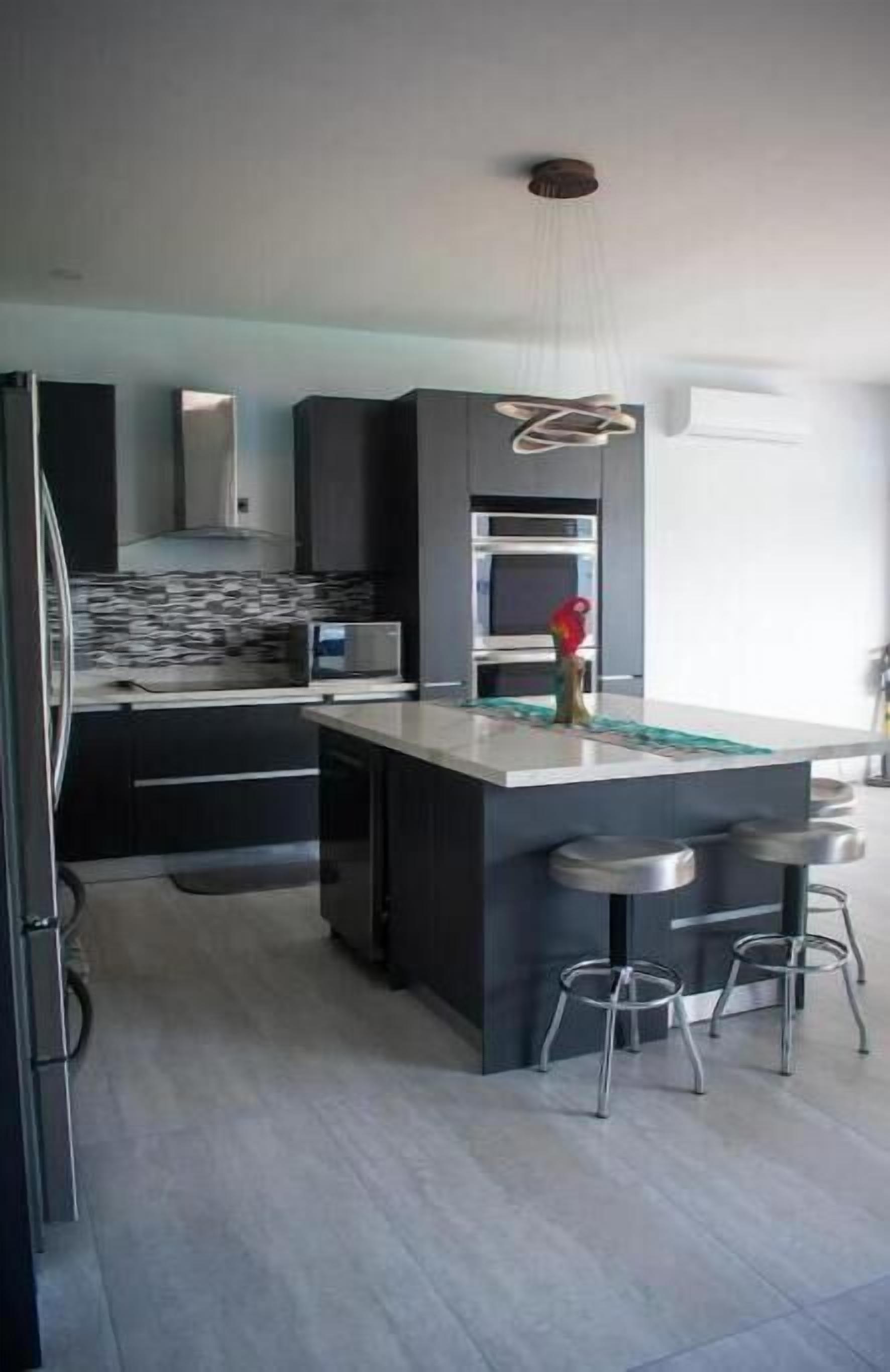 A modern kitchen with a central island, bar stools, and built-in appliances.