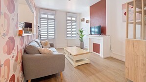 Een moderne woonkamer met een grijze bank, een houten salontafel en een televisie op een meubel.