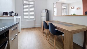 Een moderne keuken met een houten eettafel, twee stoelen, een koelkast en een koffiezetapparaat.