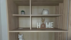Een houten plankenwand met een potplant, een decoratieve appel en een bordje met de tekst 'HOME'.