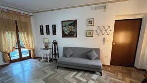 A living room with a sofa, a patterned floor, a door, and a window with curtains. - Magic Living Home Apartment on the crystal clear sea of Calabria (Campora San Giovanni)