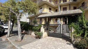 A multi-story residential building with a stone-paved entrance, a gated driveway, and balconies with railings. - Magic Living Home Apartment on the crystal clear sea of Calabria (Campora San Giovanni)