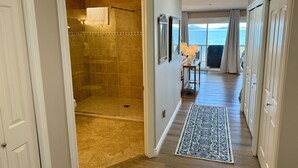 A hallway leading to a bathroom with a shower, a view of the ocean, and a patterned rug. - Mission Mountain Shores at Flathead Lake (Polson)