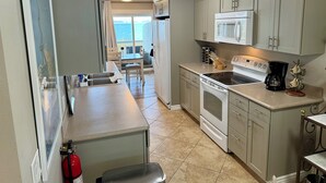 A compact kitchen with a stove, microwave, and sink. There is a dining area with a table and chairs. - Mission Mountain Shores at Flathead Lake (Polson)