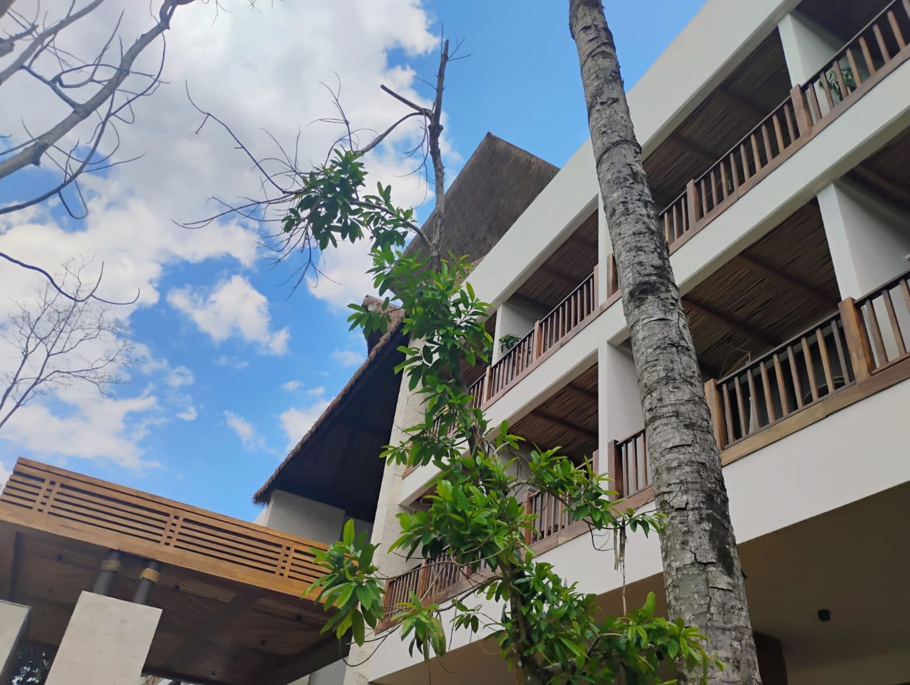 A multi-story building with balconies, a thatched roof, and a clear sky.