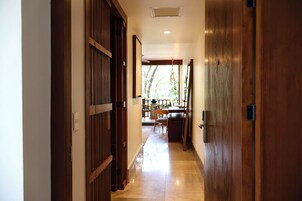 Un pasillo con puertas de madera y suelo de baldosas que conduce a un comedor con mesas y sillas.