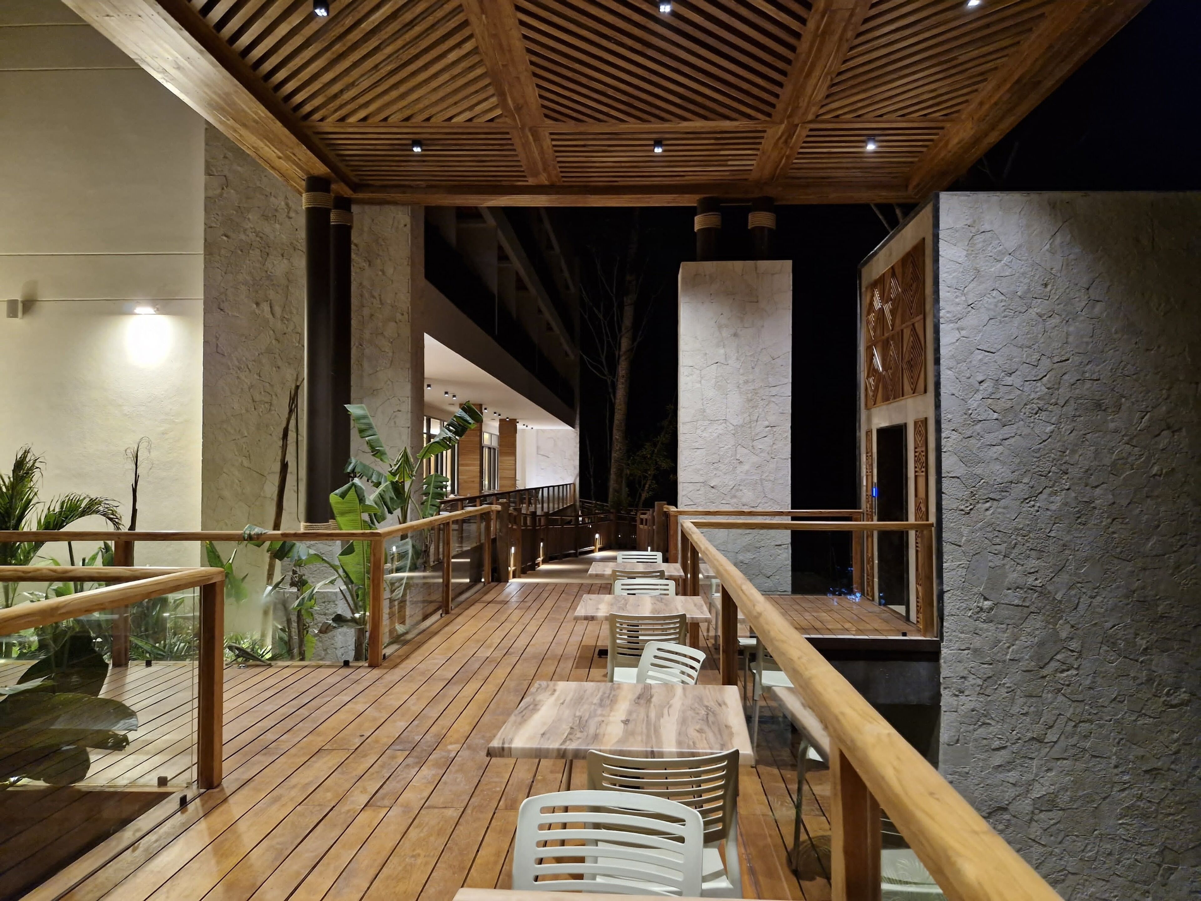 A restaurant with wooden flooring, metal railings, and tables with chairs.